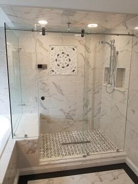 Close up view of marble tile shower with sliding glass shower door installed by Great Lakes Glass in Cleveland, Ohio